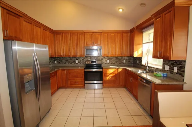 a kitchen with stainless steel appliances granite countertop a stove a sink dishwasher and a refrigerator