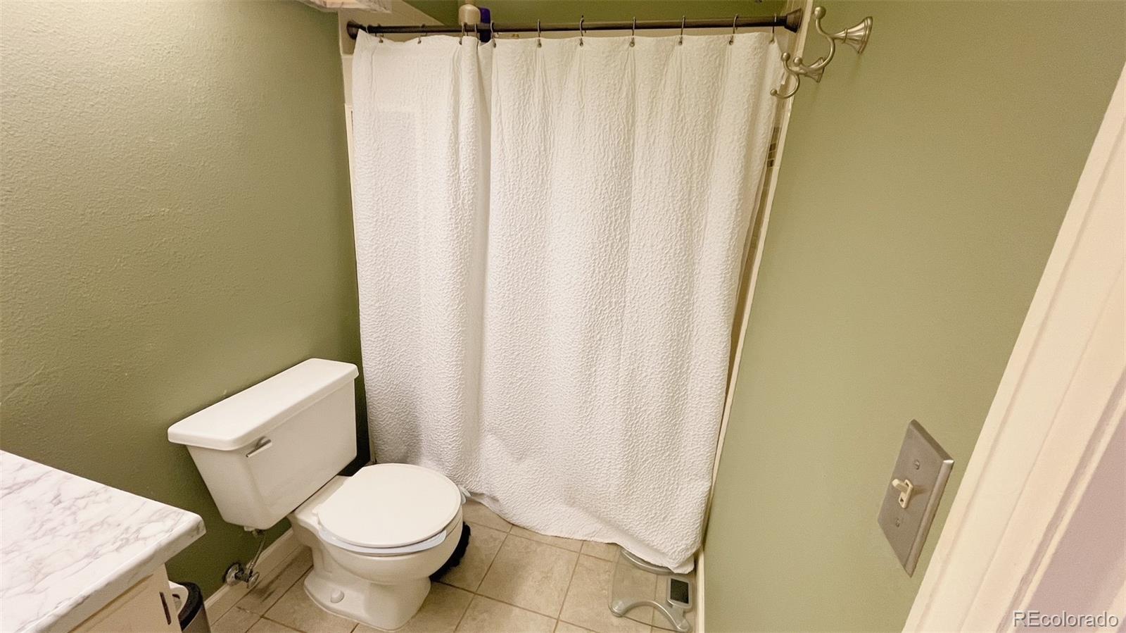 4044 South Carson Street, Unit F Aurora, CO 80014 - Photo 13 of 15 a white toilet sitting next to a shower curtain