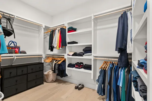 a view of walk in closet with clothes and shoes