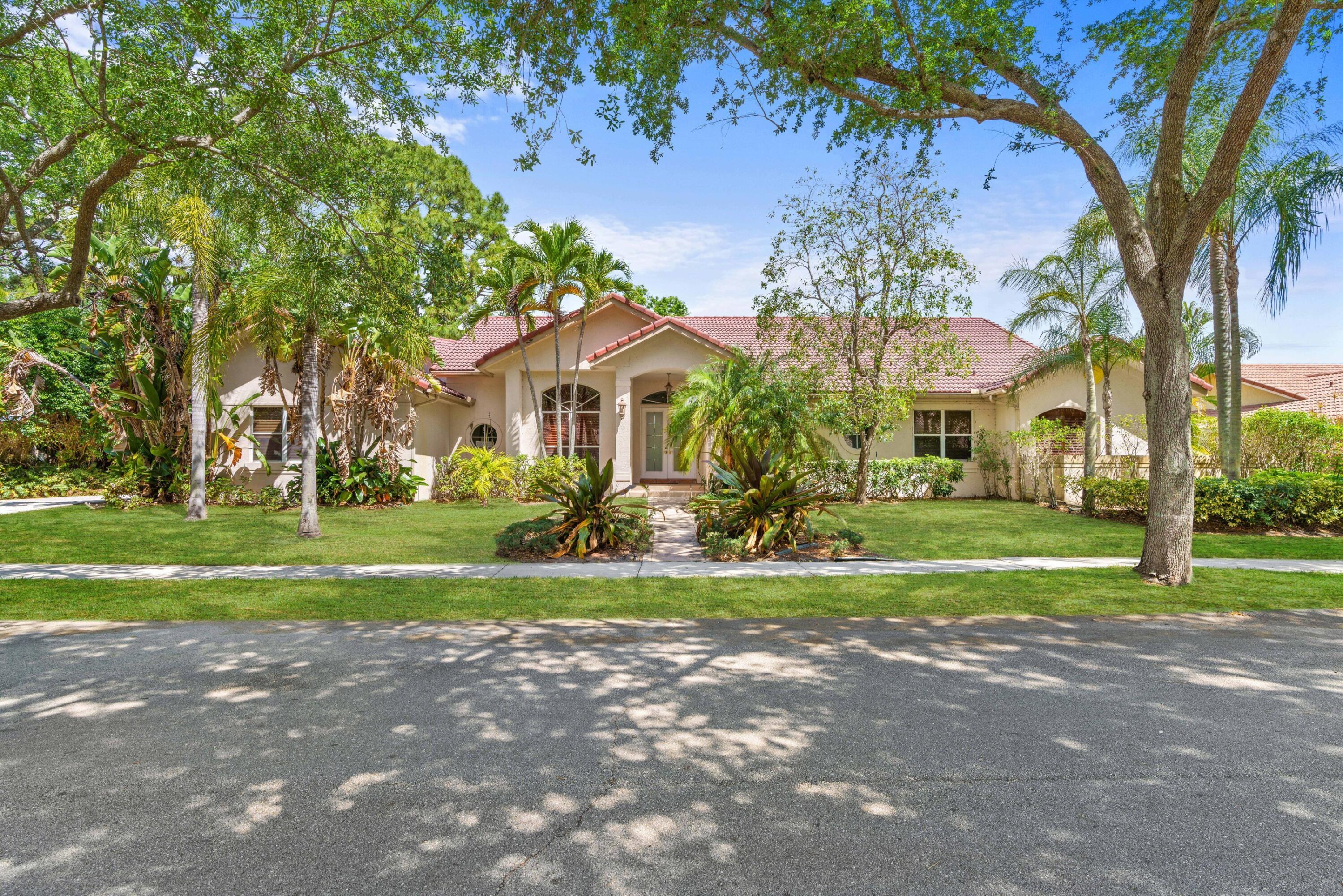 2687 Northwest 39th Street Boca Raton, FL 33434 - Photo 2 of 34 a front view of a house with a yard and large trees