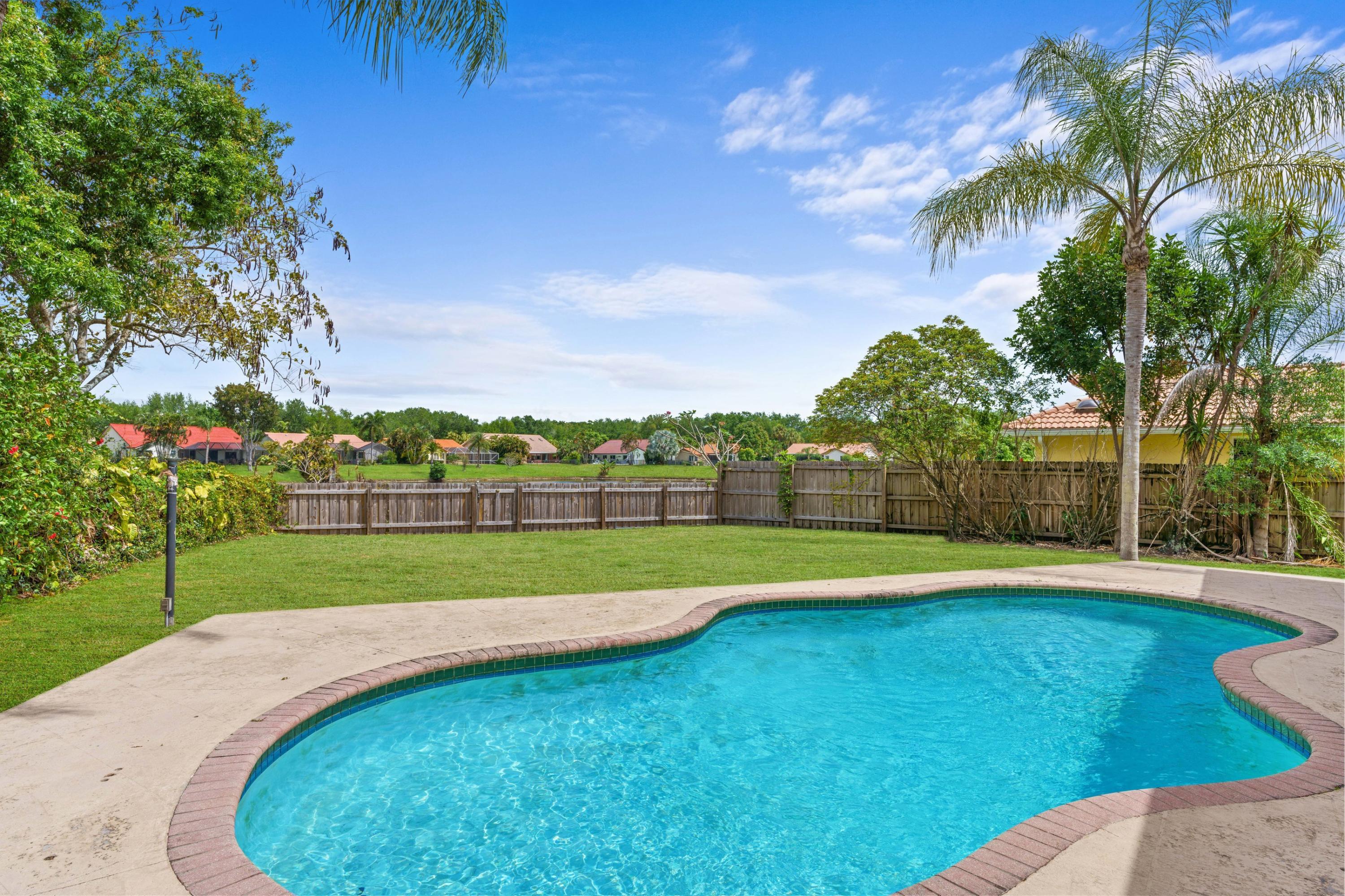2687 Northwest 39th Street Boca Raton, FL 33434 - Photo 3 of 34 a view of a swimming pool with a yard and palm trees