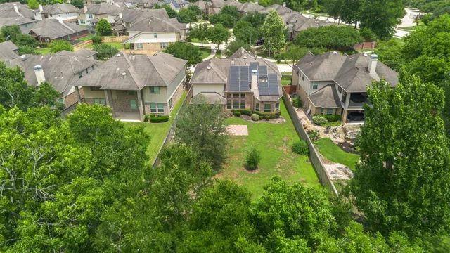 an aerial view of residential houses with outdoor space and trees all around