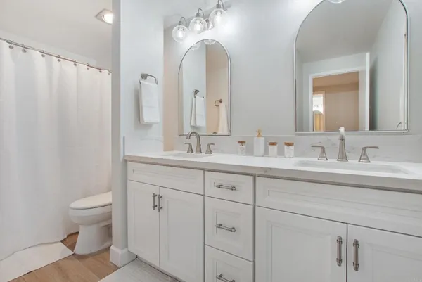 a bathroom with double vanity sink a toilet and a mirror