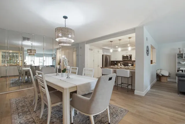 a dining room with wooden floor a chandelier a wooden table and chairs