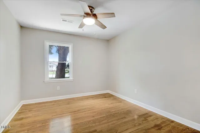 an empty room with a window and a ceiling fan