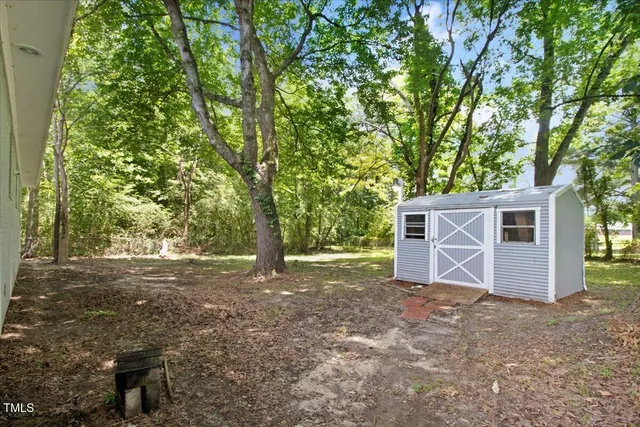 a view of a house with large tree and wooden fence