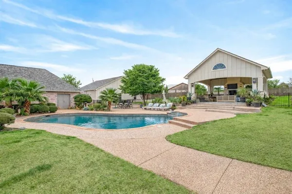 a outdoor kitchen with stainless steel appliances kitchen island granite countertop a table and chairs in it
