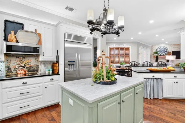 a kitchen with stainless steel appliances granite countertop a stove top oven a sink a dining table and chairs with wooden floor