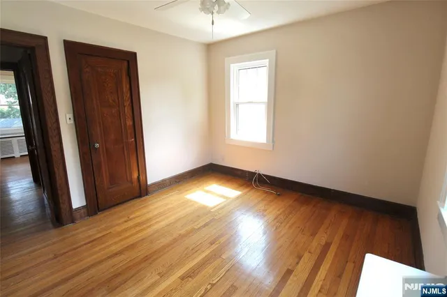an empty room with wooden floor and windows with curtains