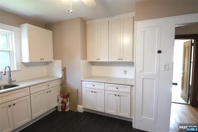 a kitchen with white cabinets and sink