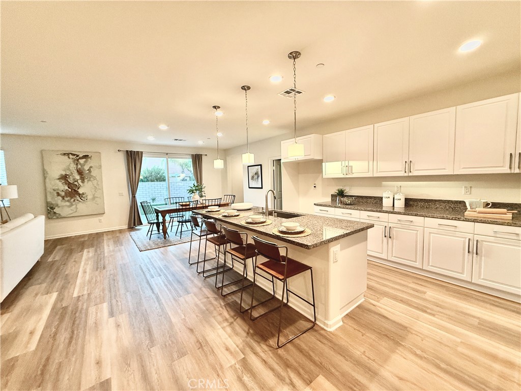 36237 Sunset Ridge Court Wildomar, CA 92595 - Photo 4 of 41 a kitchen with stainless steel appliances granite countertop a stove top oven a sink dishwasher and white cabinets with wooden floor