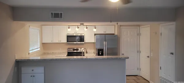 a kitchen with stainless steel appliances a sink a refrigerator and a window