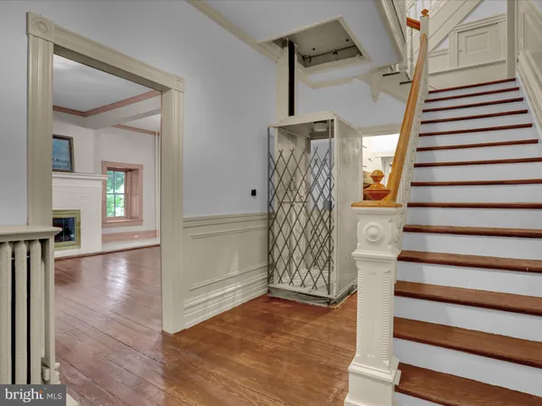 a view of an empty room with wooden floor fireplace and a window