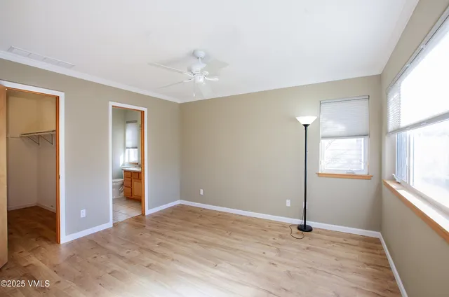 a view of an empty room with window and wooden floor