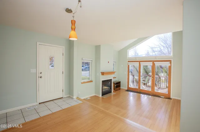 a view of an empty room with window and kitchen view