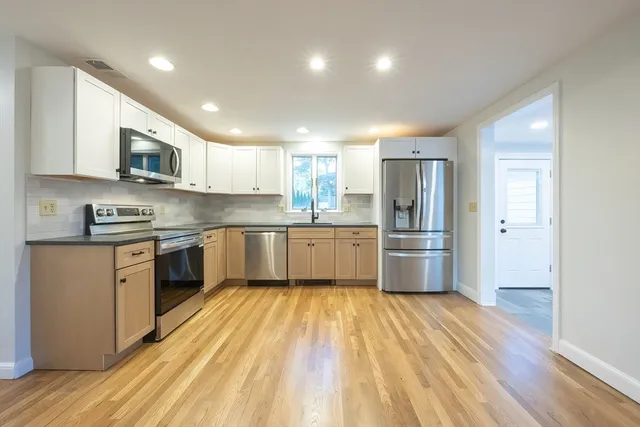 a kitchen with stainless steel appliances granite countertop a sink cabinets and wooden floor