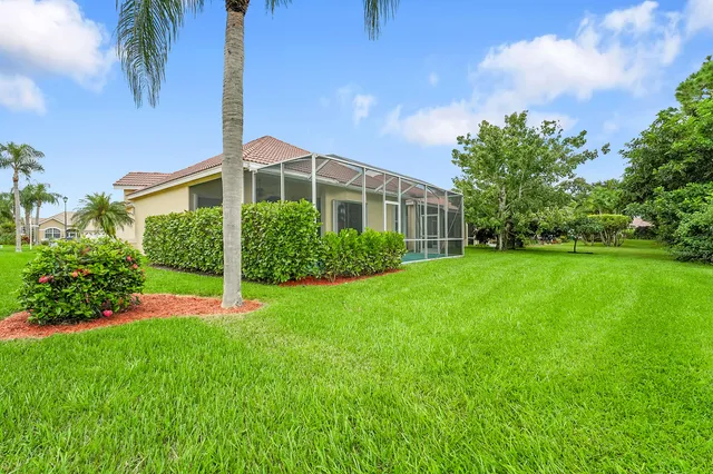 a front view of a house with a yard and palm trees