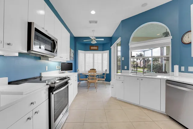 a kitchen with stainless steel appliances granite countertop a stove top oven a sink a dining table and chairs with wooden floor