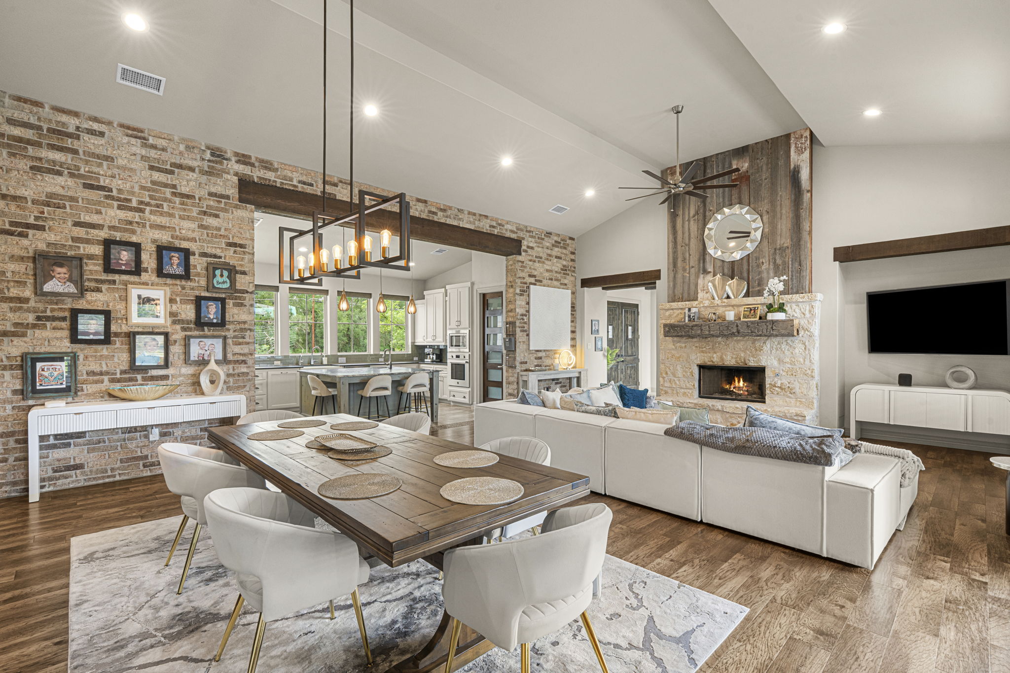 16202 Remuda Trail Buda, TX 78610 - Photo 7 of 40 Spacious open-plan living area featuring hardwood flooring, a brick accent wall, and a natural stone fireplace with a wood mantel