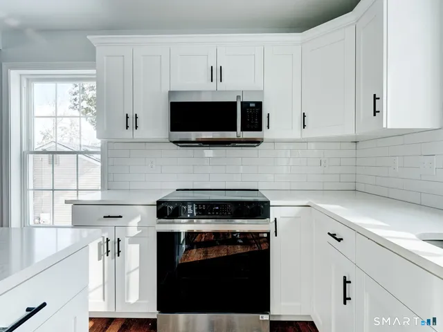 a kitchen with cabinets stainless steel appliances a sink and a window