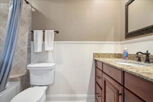 a bathroom with a granite countertop toilet sink and mirror