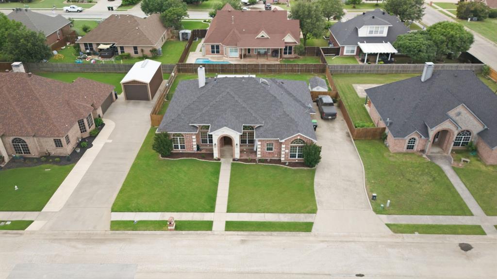 603 Cedar Drive Pilot Point, TX 76258 - Photo 36 of 39 Red brick home featuring a prominent arched entry, a dark shingle roof, and a meticulously maintained front lawn with a central walkway