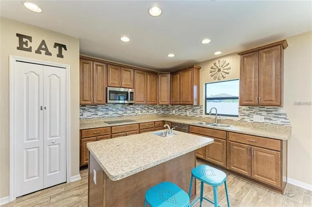 a kitchen with stainless steel appliances granite countertop a stove a sink dishwasher and a refrigerator with wooden floor