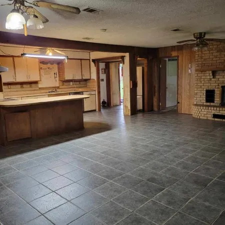 a large hall with stainless steel appliances granite countertop a sink and cabinets