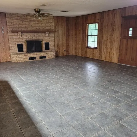 a view of an empty room with a fireplace and a window