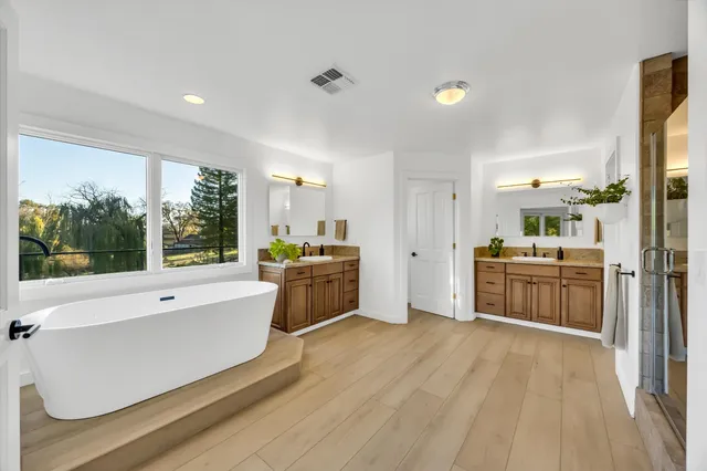 a view of a patio with table and chairs under an umbrella with large trees