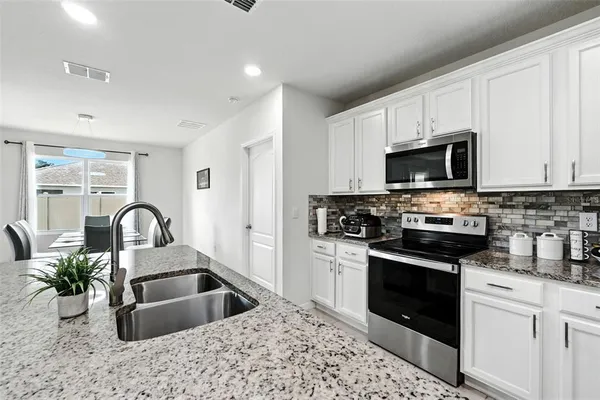 a kitchen with granite countertop white cabinets stainless steel appliances and a counter space
