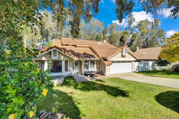 a front view of a house with a yard and large trees