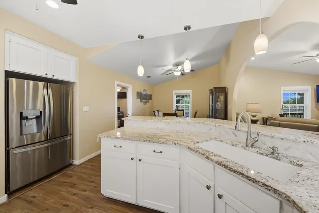 a kitchen with stainless steel appliances kitchen island granite countertop a stove top oven a sink dishwasher and a refrigerator with wooden floor