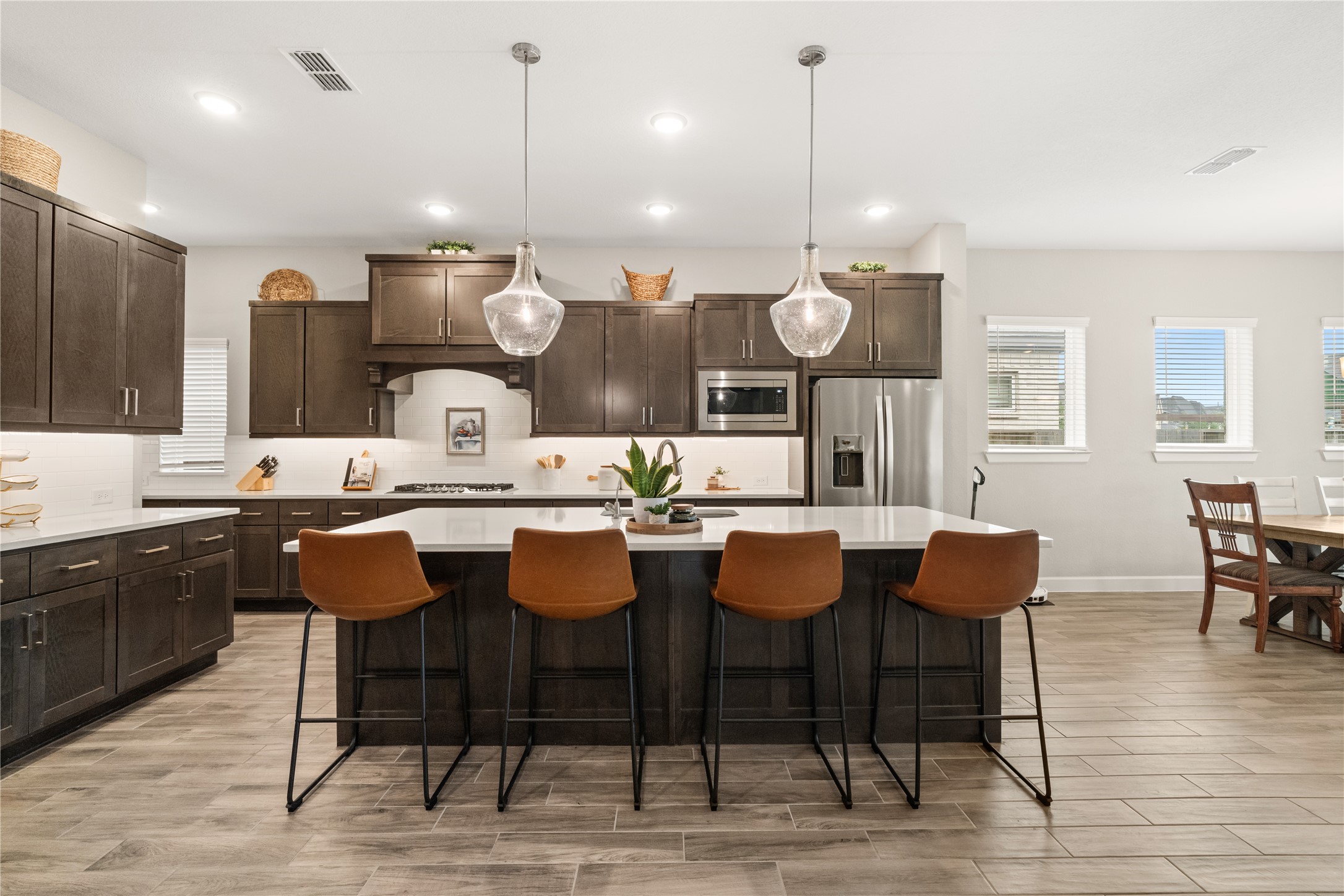 3118 Swift Way Katy, TX 77493 - Photo 5 of 34 Kitchen – A stunning open-concept kitchen featuring a large center island, quartz countertops, dark wood cabinetry, and stylish pendant lighting, perfect for both cooking and entertaining.