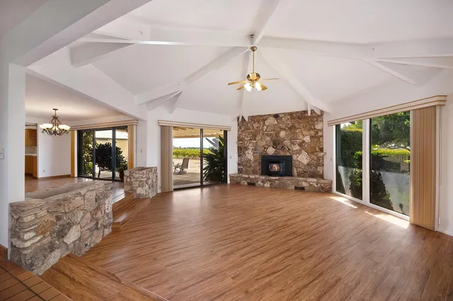 a view of a room with wooden floor fireplace and windows