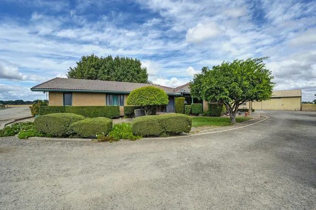 a front view of a house with a garden and trees