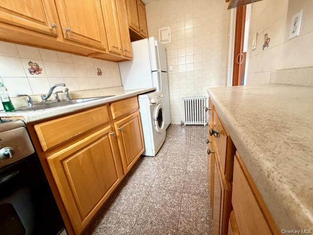 67-20 218th Street, Unit LOWR Queens, NY 11364 - Photo 3 of 17 Kitchen with light countertops, washer / dryer, radiator heating unit, stove, and granite tiled floors