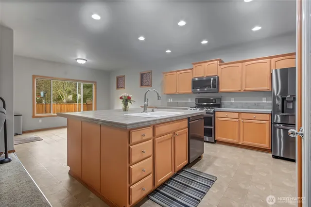 a kitchen with stainless steel appliances granite countertop a stove a sink a refrigerator and white cabinets