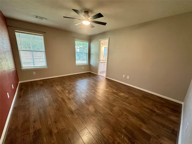 an empty room with wooden floor and windows