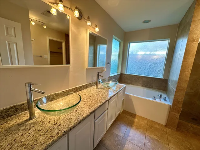 a bathroom with a granite countertop tub sink and mirror