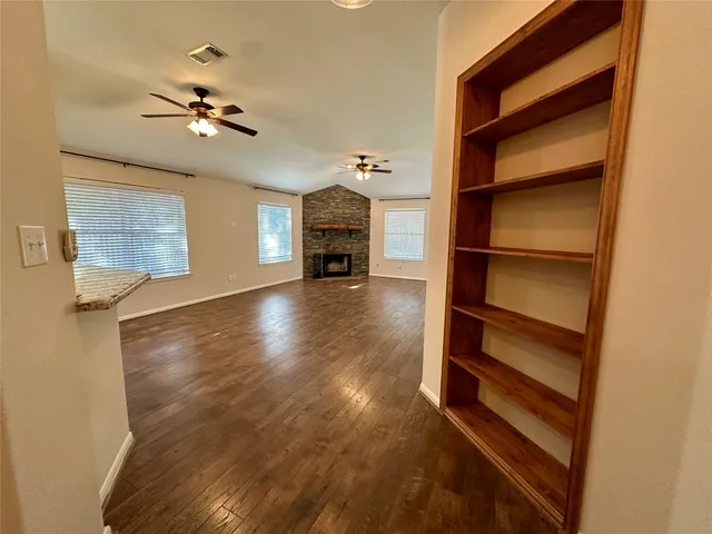 a view of an empty room with a window and wooden floor