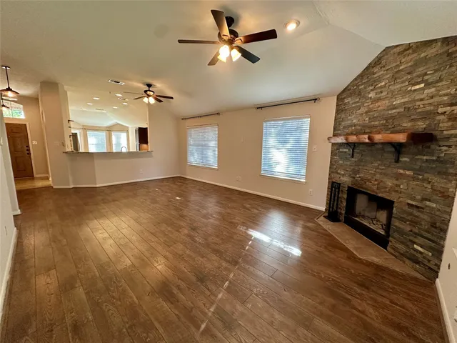 a view of a livingroom with a fireplace a ceiling fan and windows