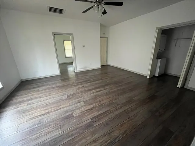 an empty room with wooden floor and a ceiling fan