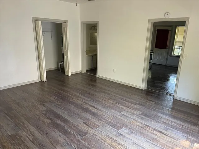 a view of an empty room with wooden floor and closet
