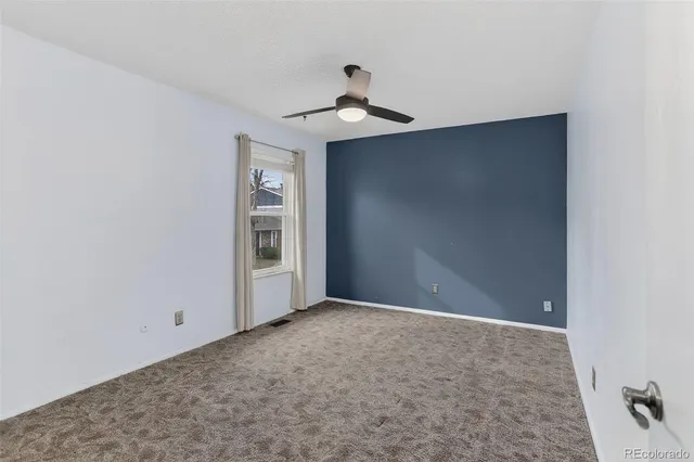 a view of an empty room with chandelier fan