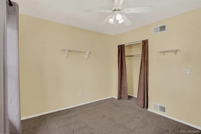 an empty room with a ceiling fan and a window