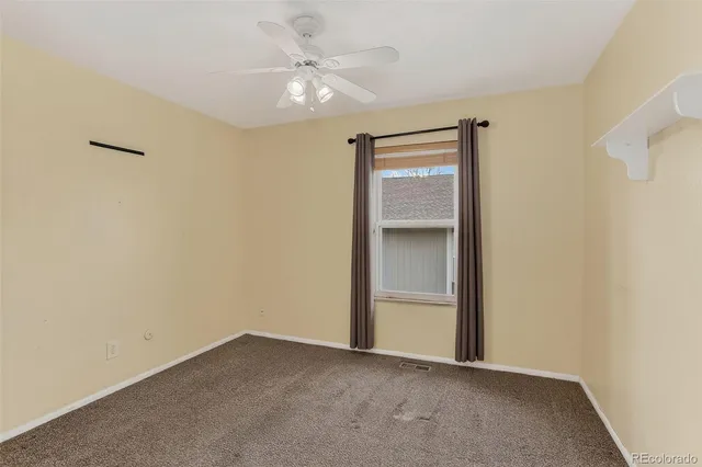 an empty room with a ceiling fan and a window