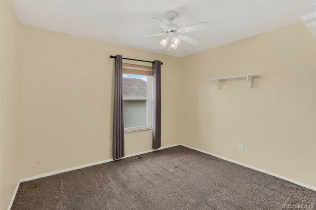 an empty room with a ceiling fan and carpet