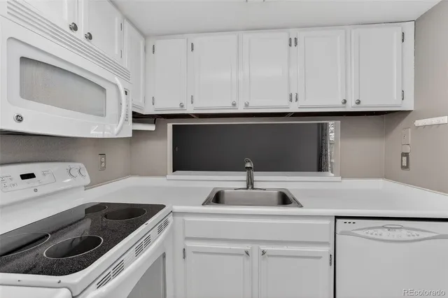 a kitchen with white cabinets and sink