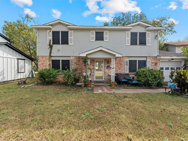 a white house that has a small yard and large trees with wooden fence